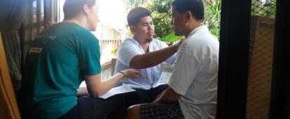 A Projects Abroad student on the Physiotherapy internship for high school students in the Philippines takes notes during a consultation. A student on the Physiotherapy internship for teenagers in the Philippines, observes as staff assist a man.